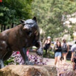 Panther statue on campus with students in the background.